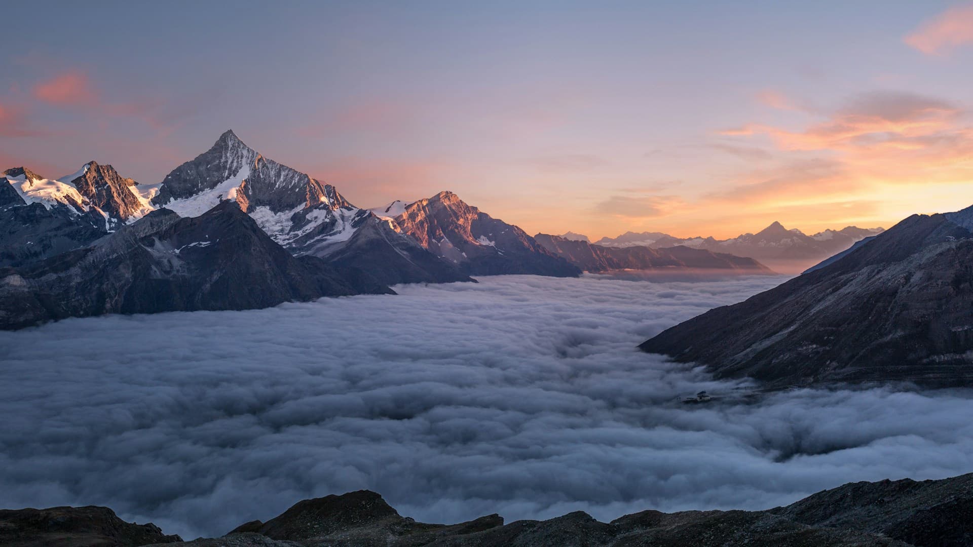 Mountain peaks at first light above the clouds